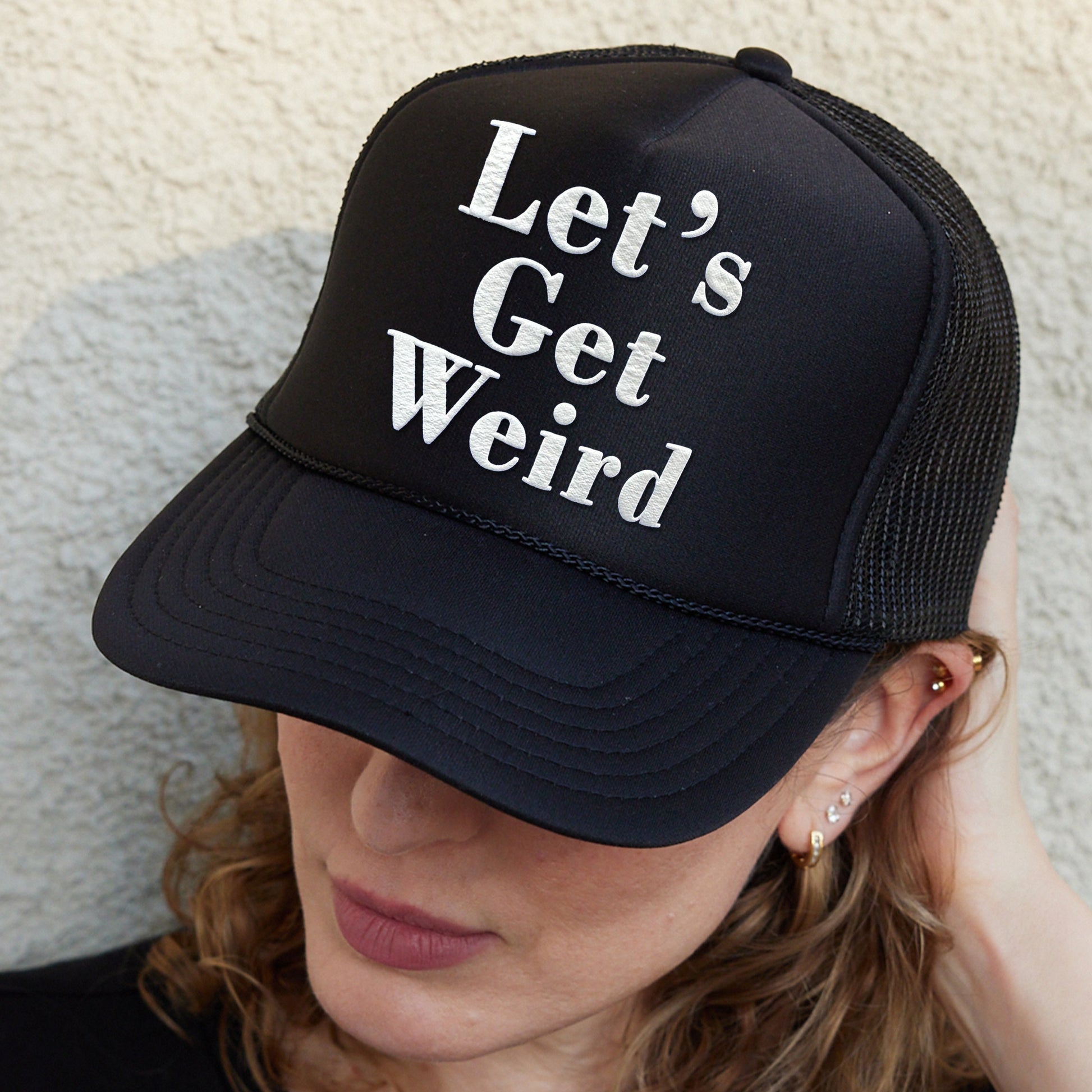 a woman wearing a hat that says let&#39;s get weird