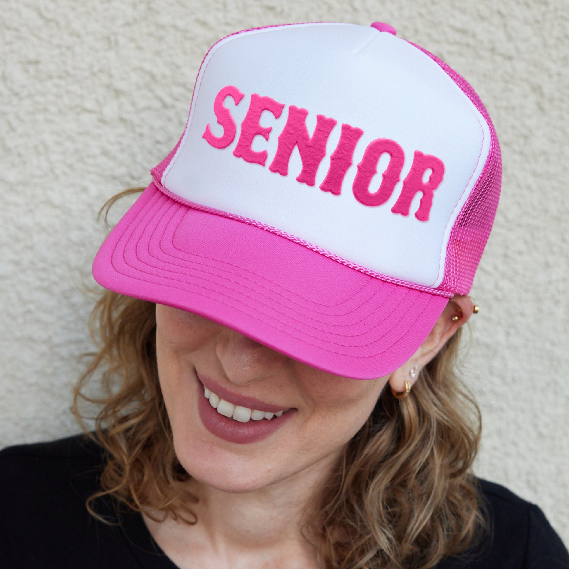 a woman wearing a pink and white hat with the word senior on it