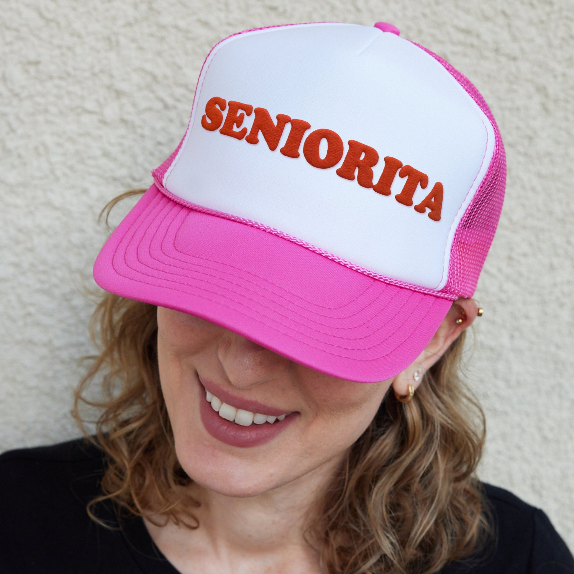 a woman wearing a pink and white trucker hat
