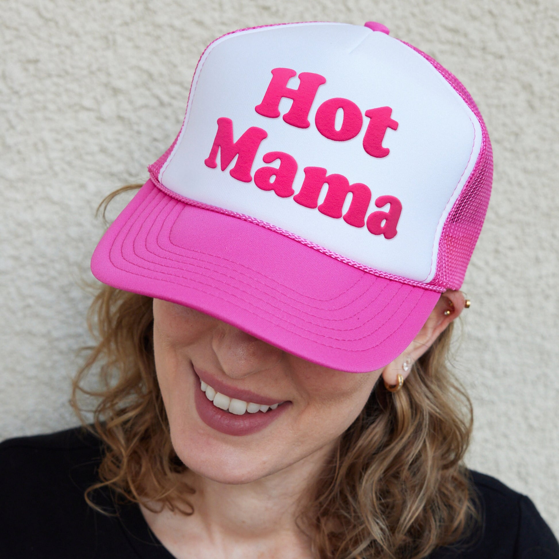 a woman wearing a pink and white hat with the words hot mama on it