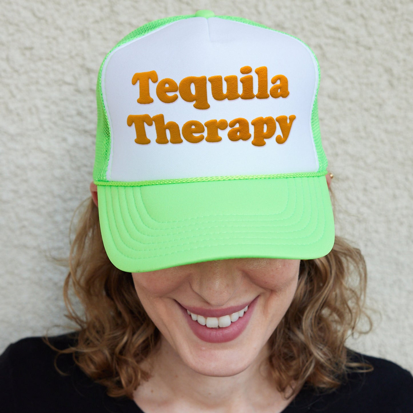 a woman wearing a green and white trucker hat that says tequila therapy