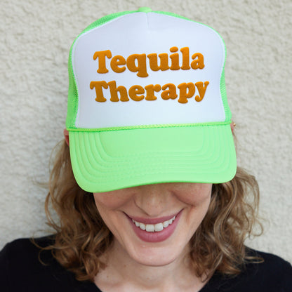 a woman wearing a green and white trucker hat that says tequila therapy