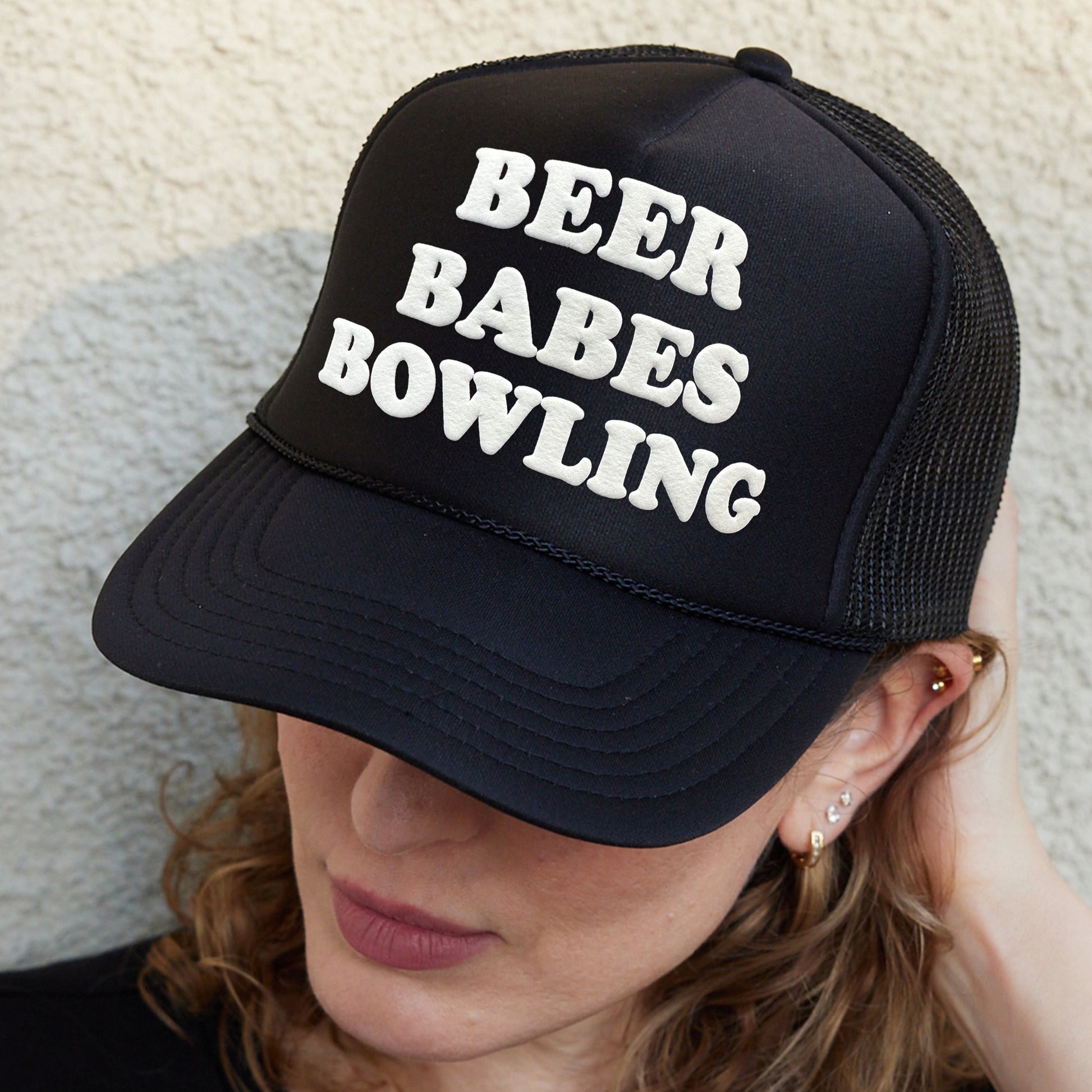 a woman wearing a hat that says beer babes bowling