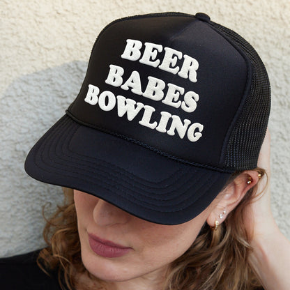 a woman wearing a hat that says beer babes bowling