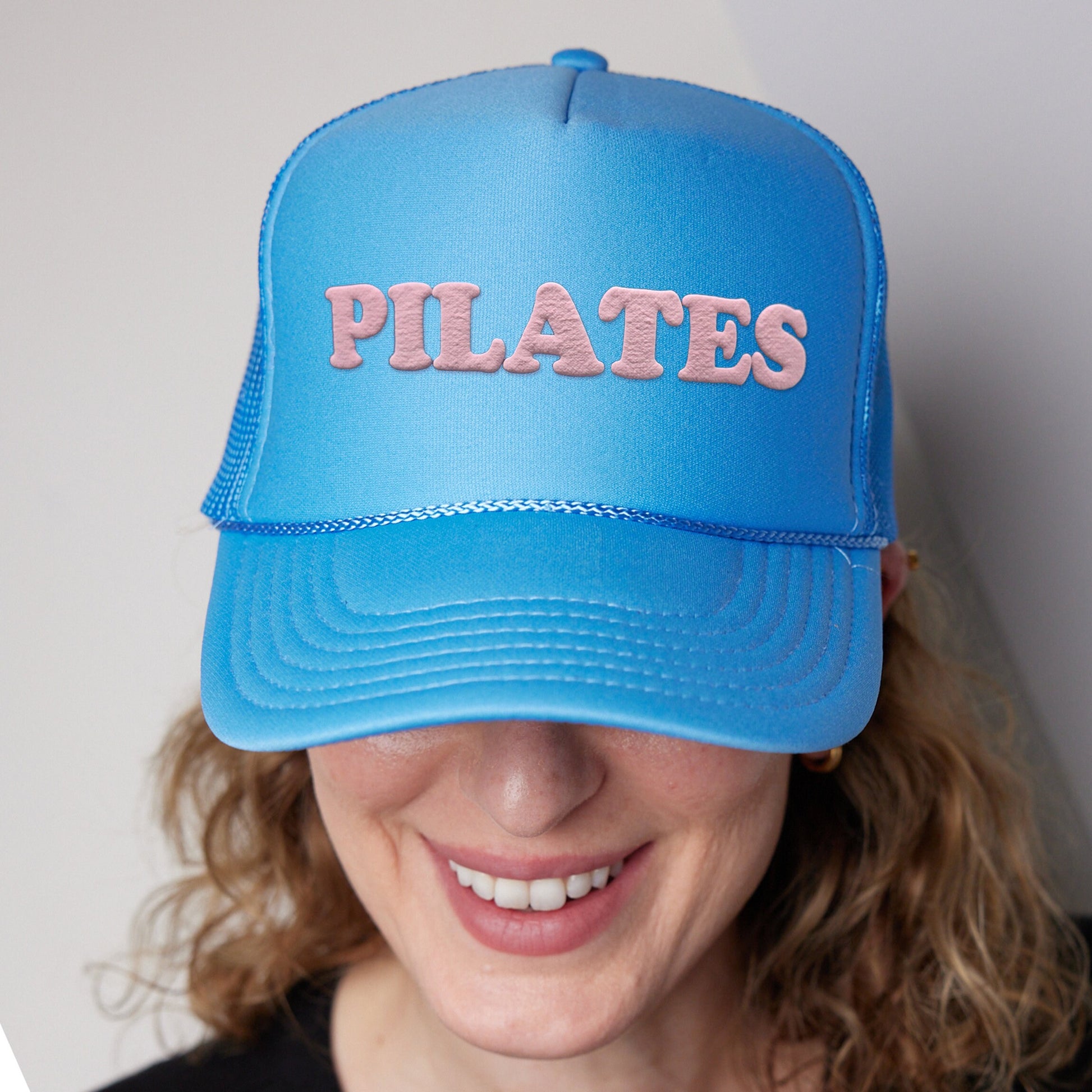 a woman wearing a blue hat with the word pilates on it