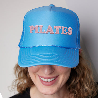 a woman wearing a blue hat with the word pilates on it