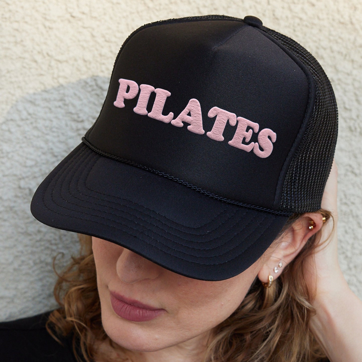 a woman wearing a hat with the word pilates on it