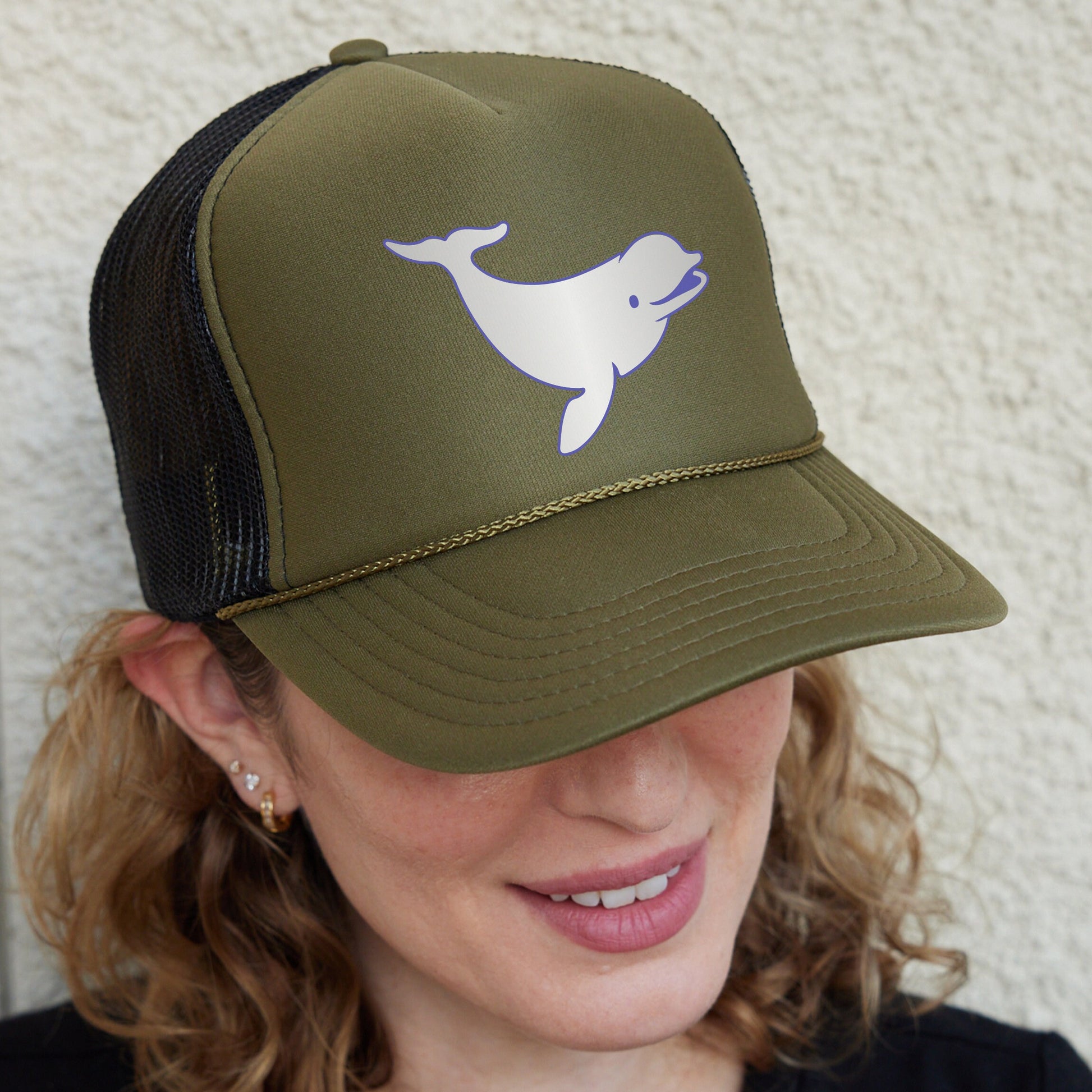 a woman wearing a trucker hat with a dolphin on it