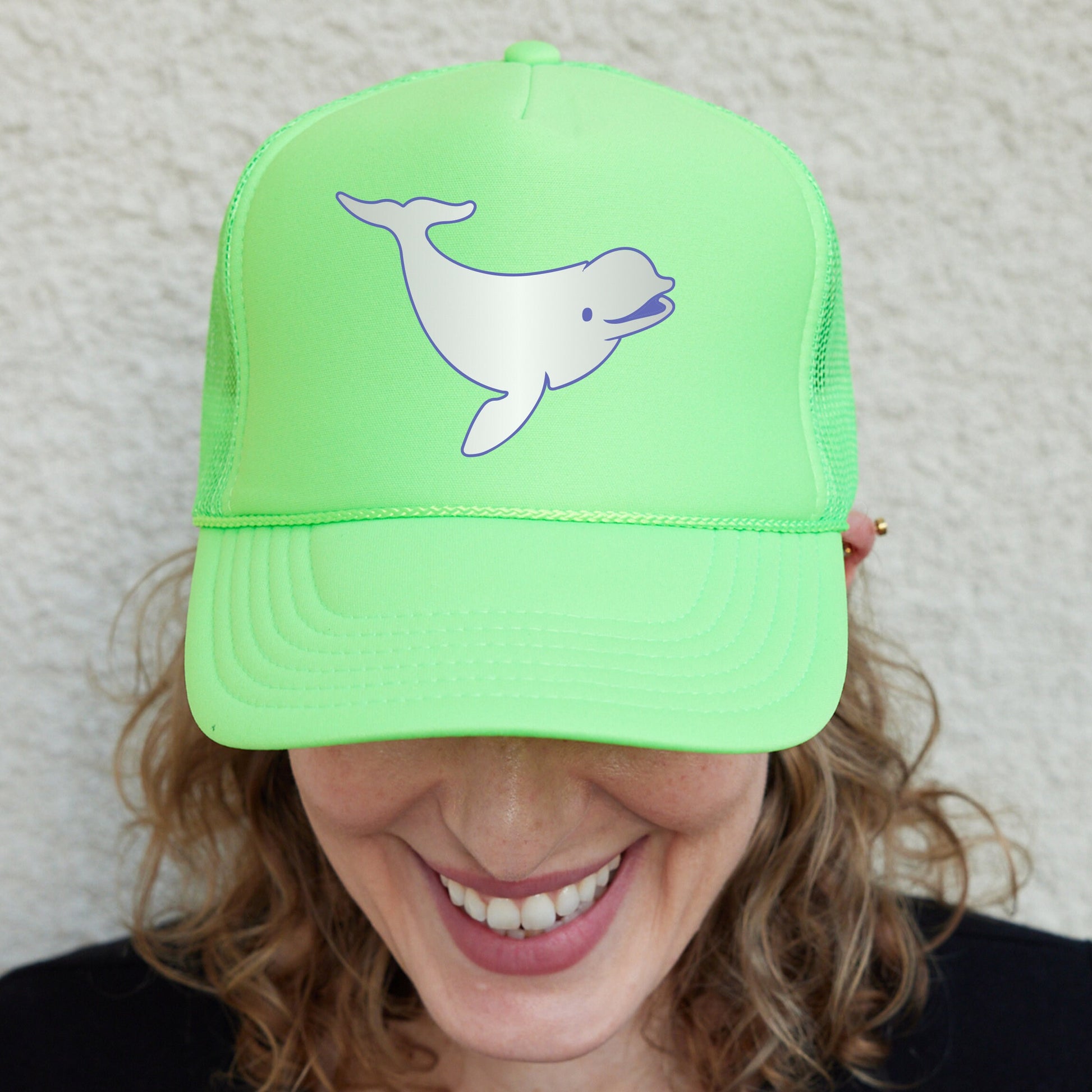 a smiling woman wearing a green hat with a whale on it