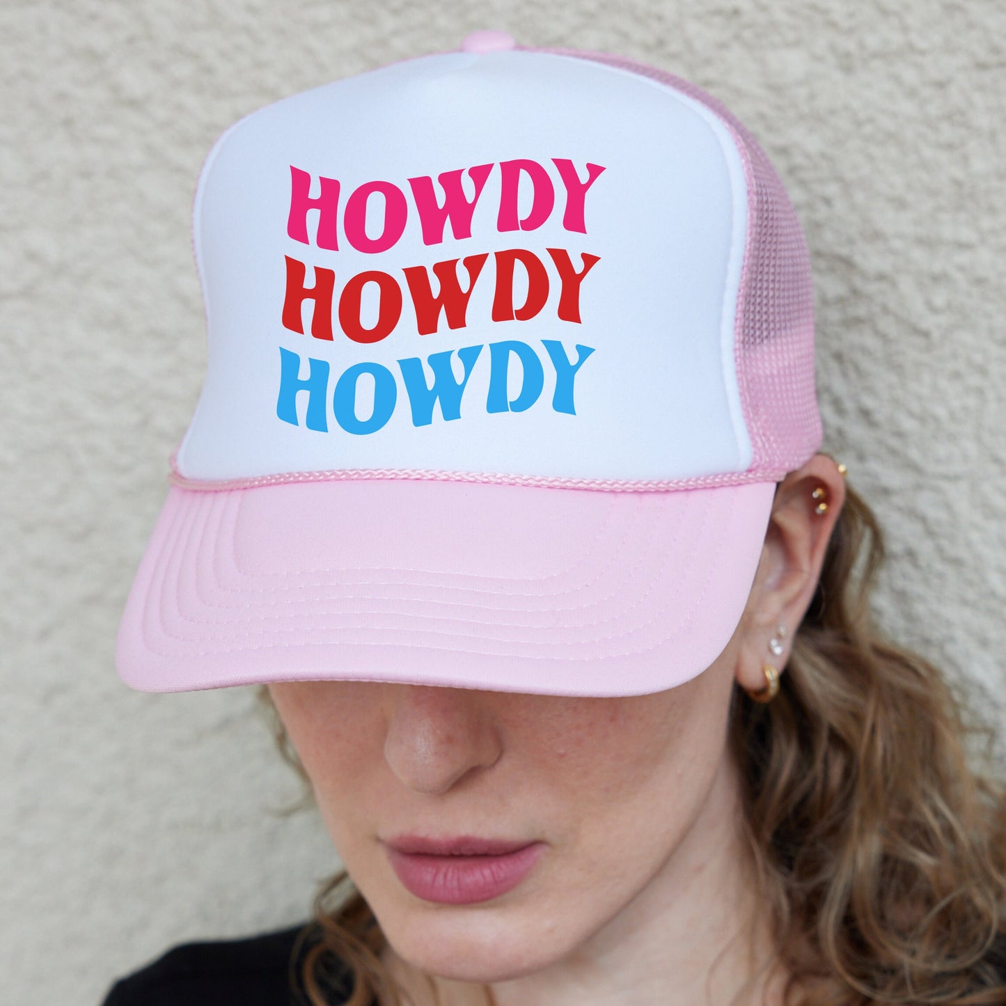 a woman wearing a pink and white trucker hat
