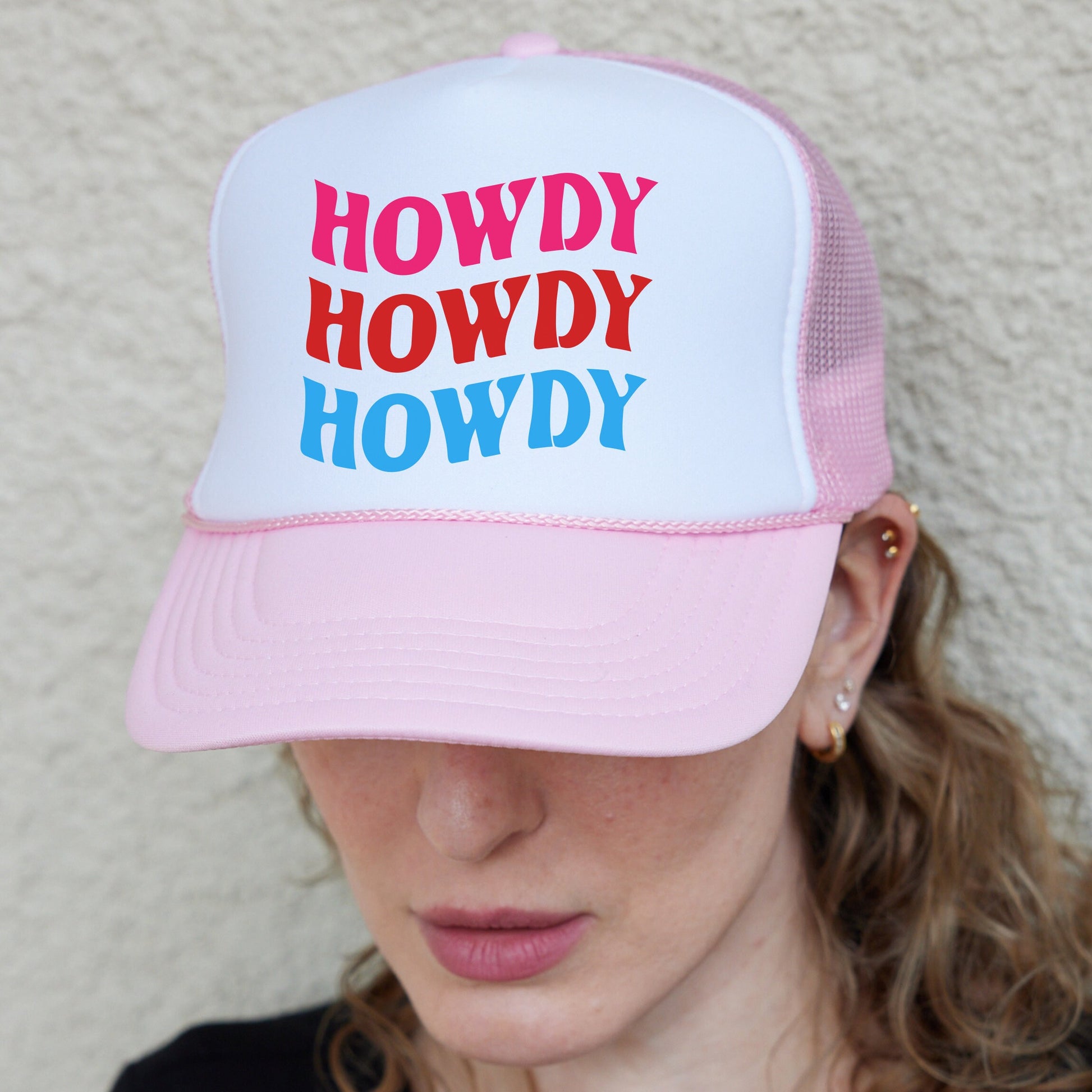a woman wearing a pink and white trucker hat