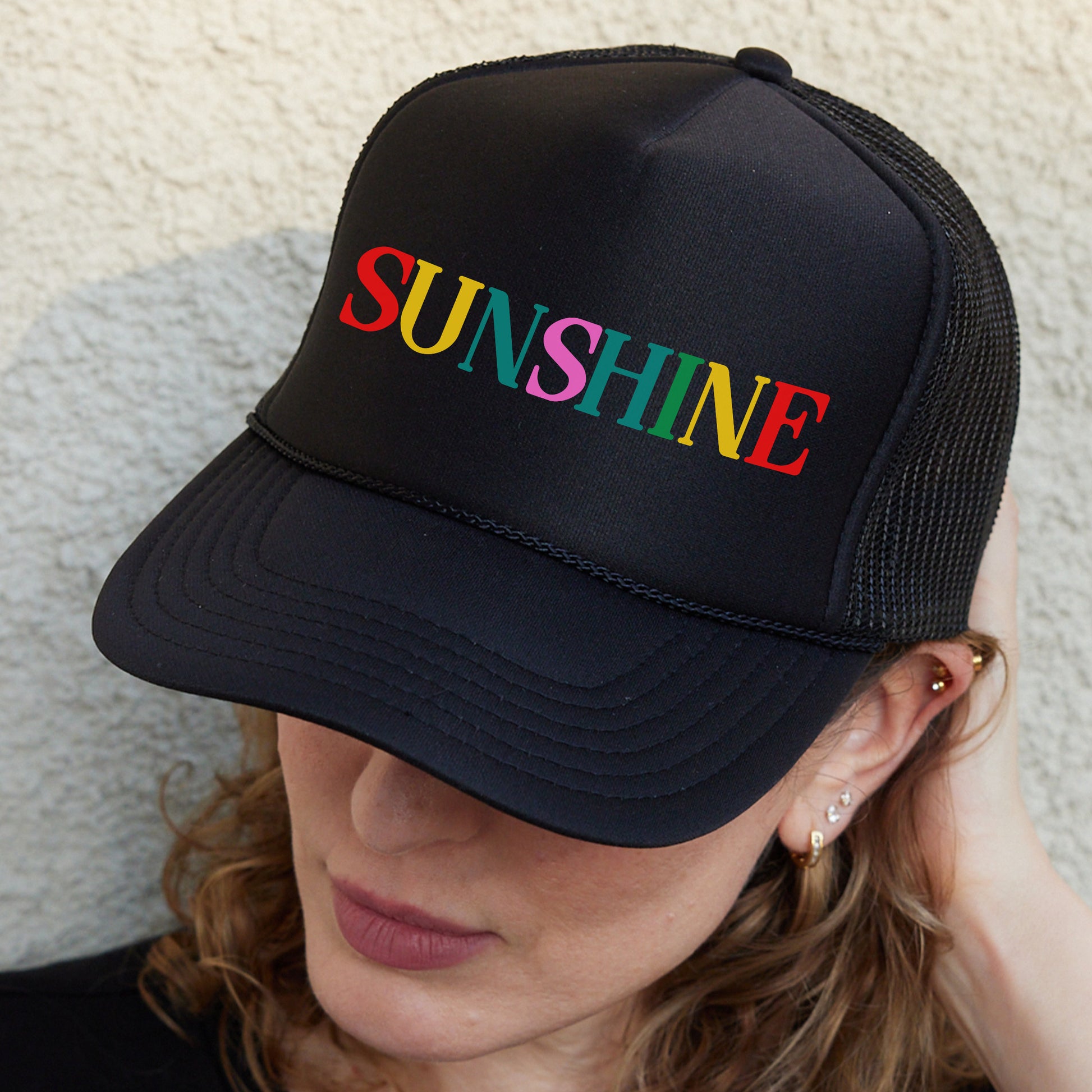 a woman wearing a black hat with the word sunshine on it