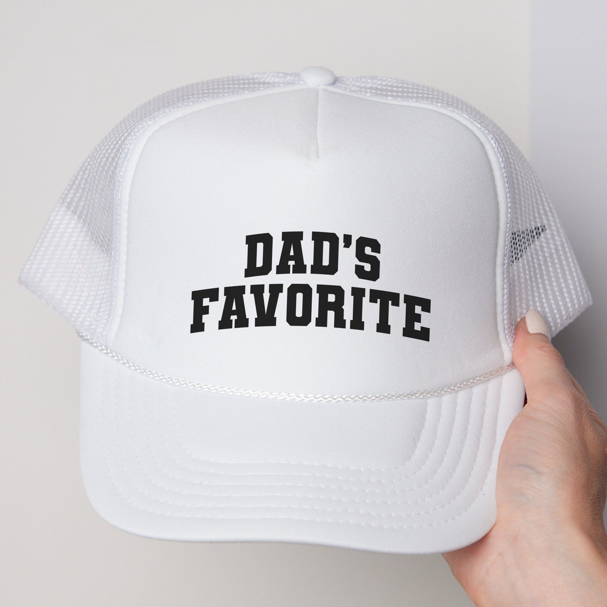 a person holding a white hat that says dad&#39;s favorite