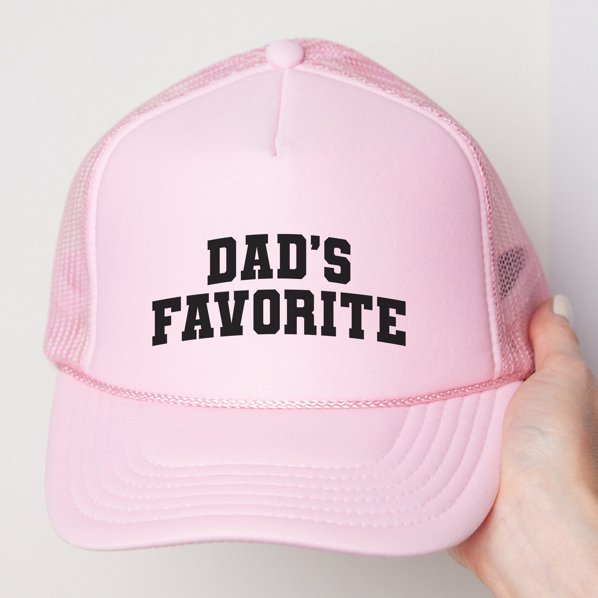 a person holding a pink hat that says dad&#39;s favorite