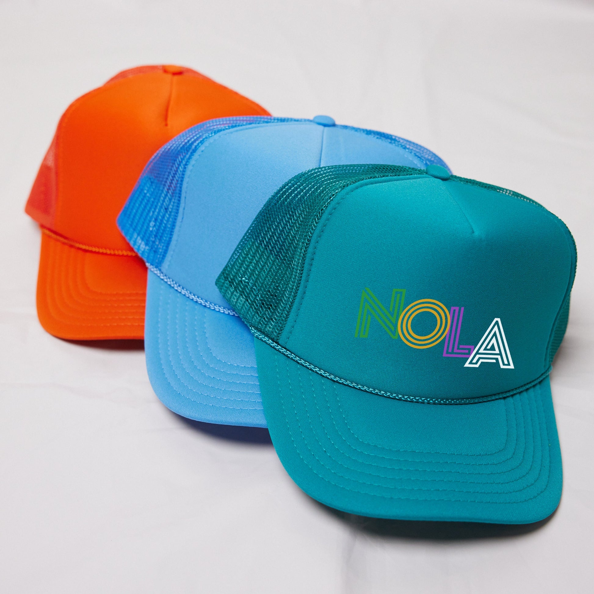 three different colored hats sitting on a white surface