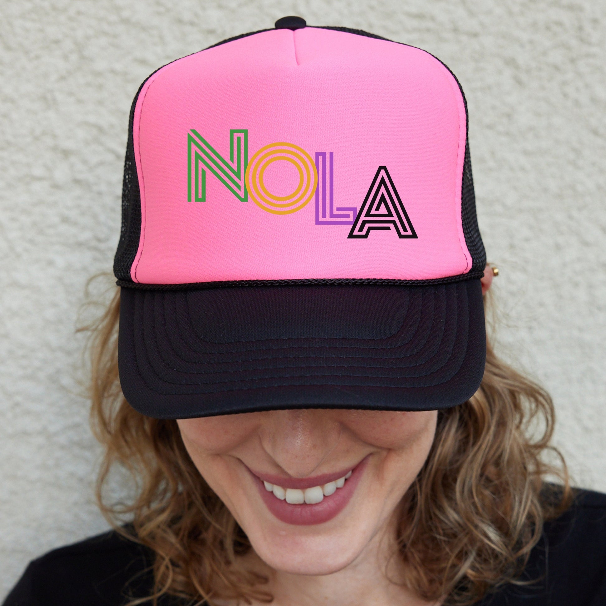 a woman wearing a pink and black hat with nola on it