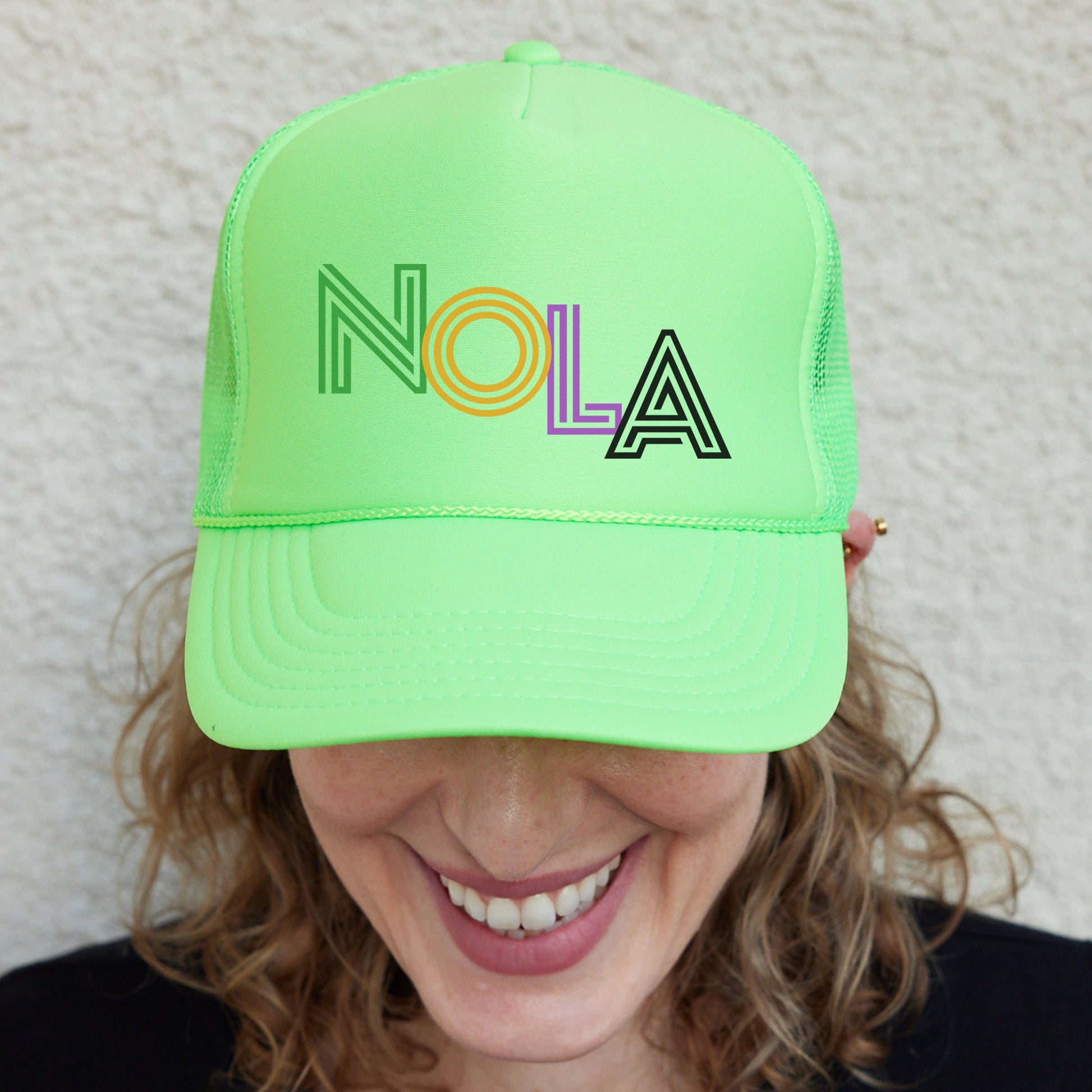 a woman wearing a neon green hat with the word nola on it