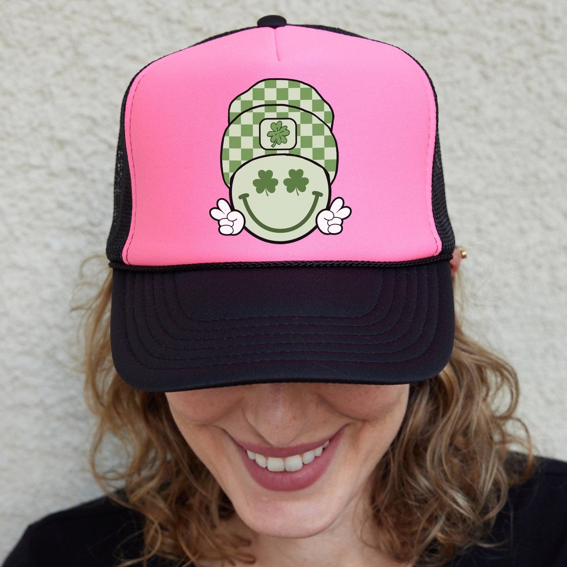 a smiling woman wearing a pink and black hat