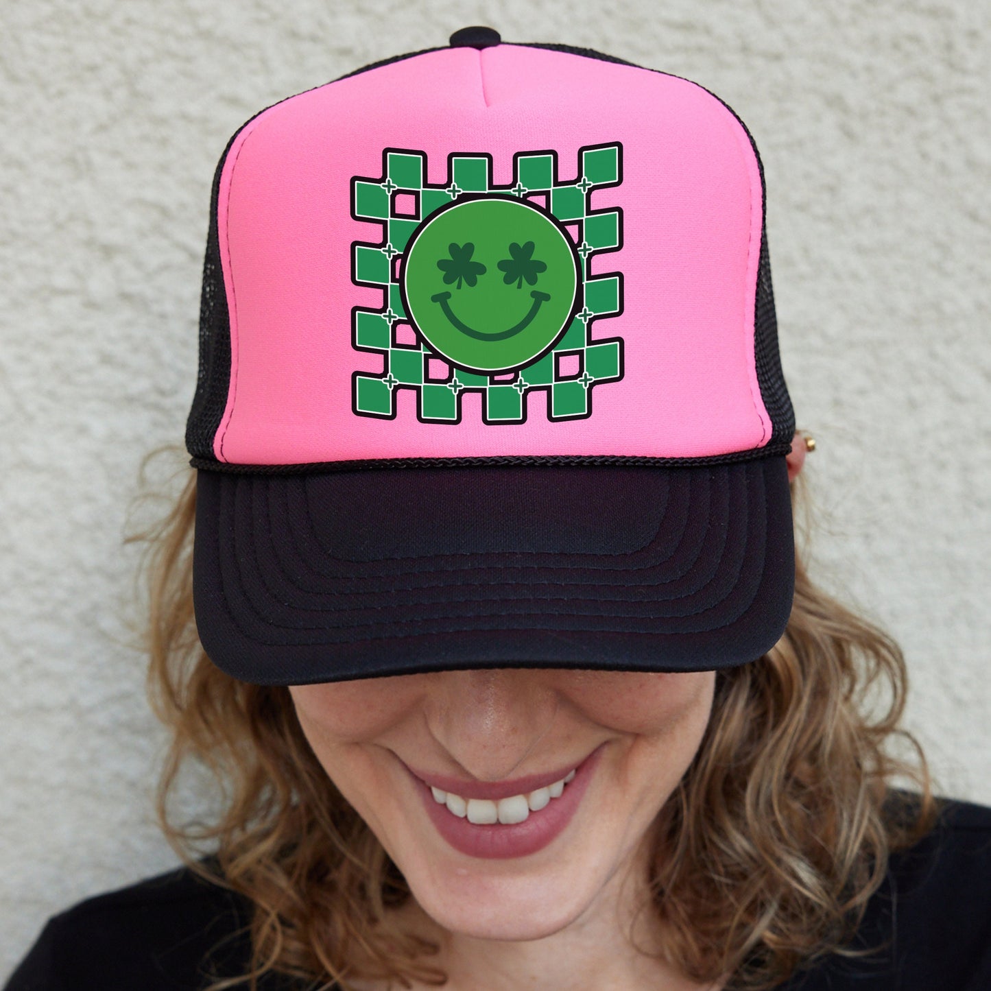 a woman wearing a pink hat with a green smiley face