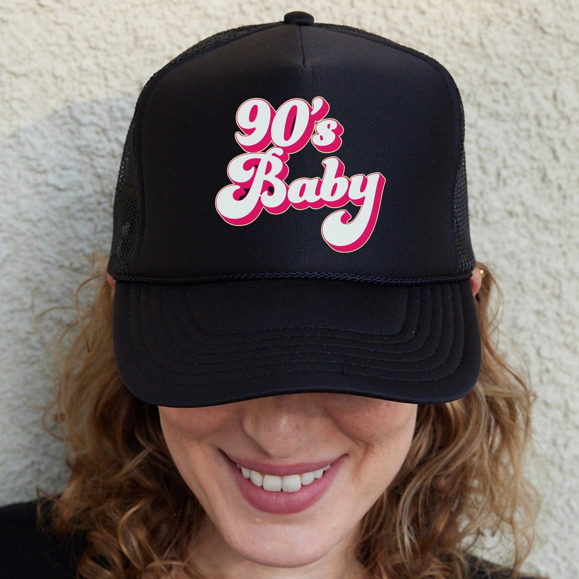 a woman wearing a black trucker hat with the words 90&#39;s baby on