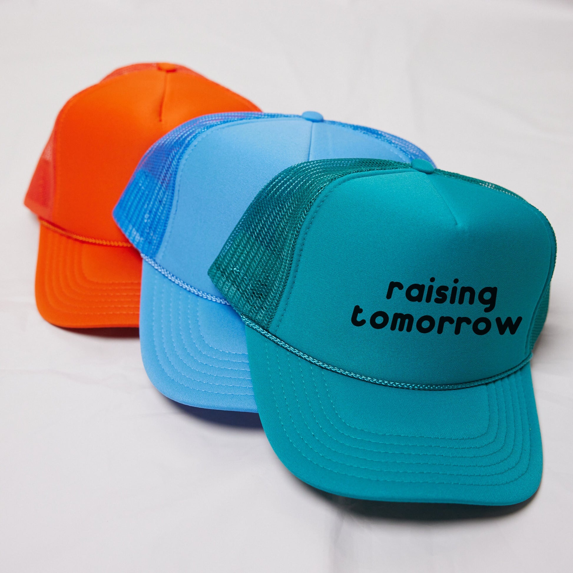three hats that say raising tomorrow on them