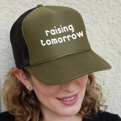 a woman wearing a trucker hat that says raising tomorrow