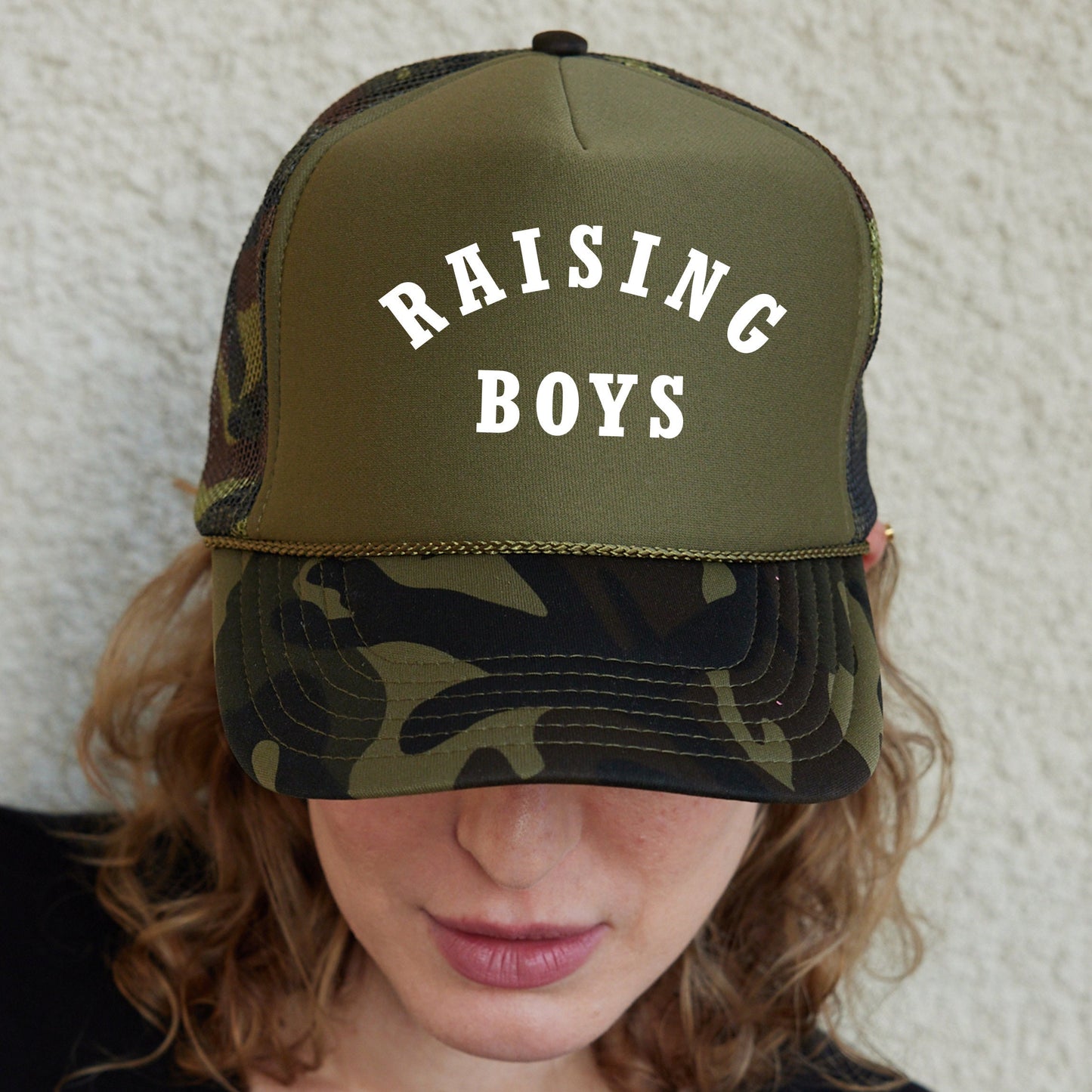 a woman wearing a hat that says raising boys