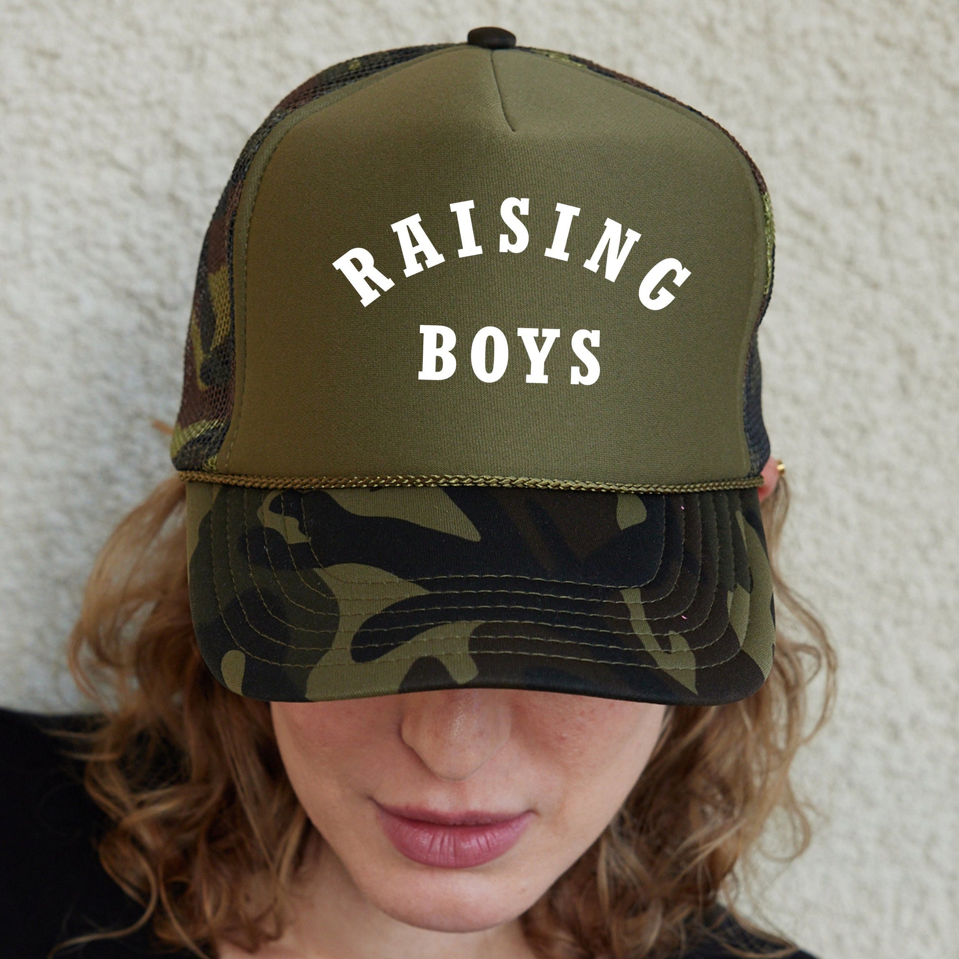 a woman wearing a hat that says raising boys