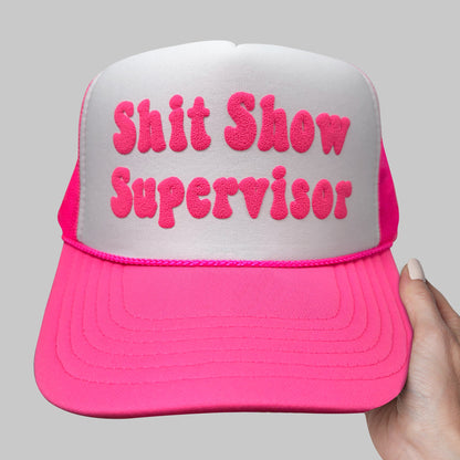 a pink and white hat that says shit show supervisor