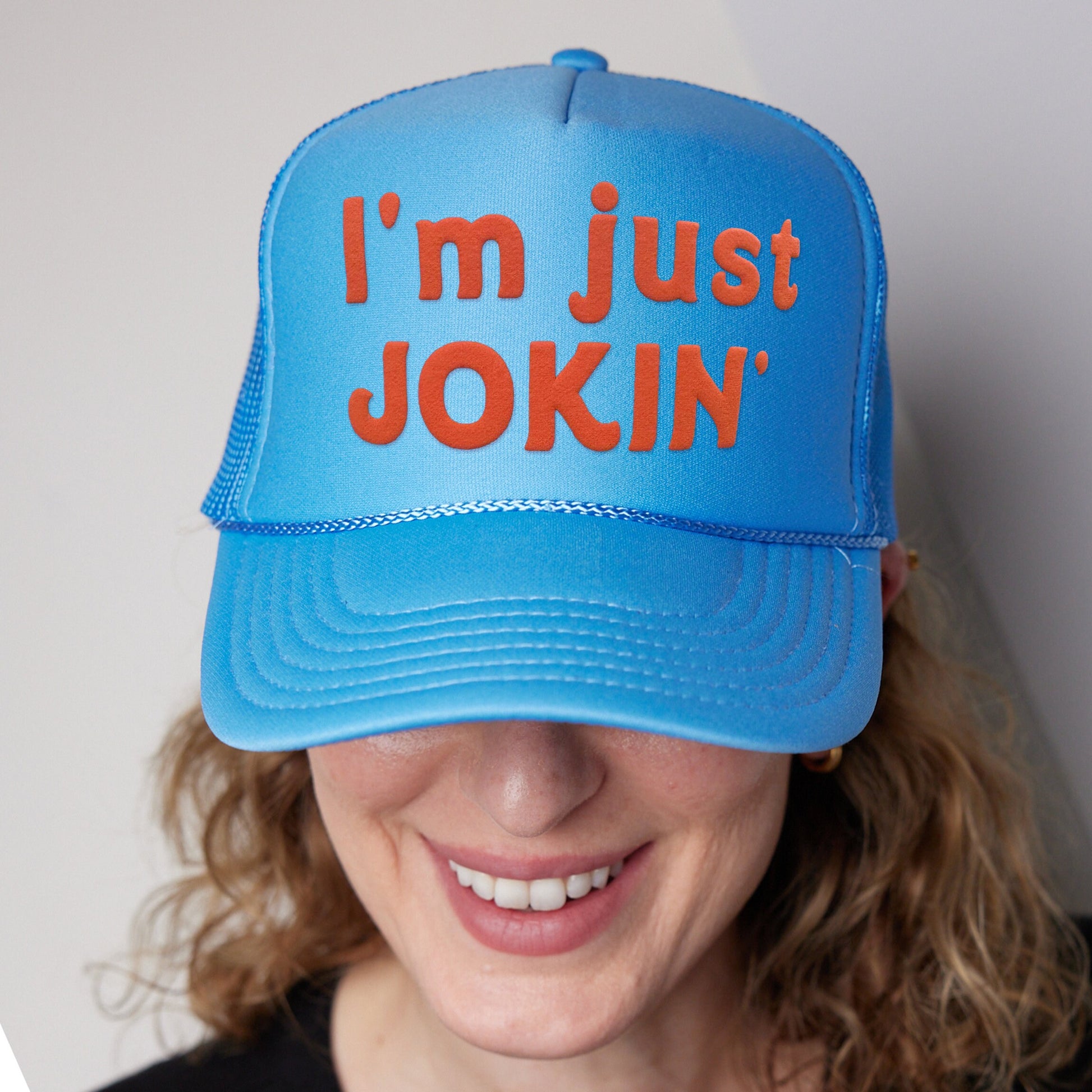 a woman wearing a blue hat that says i&#39;m just joking