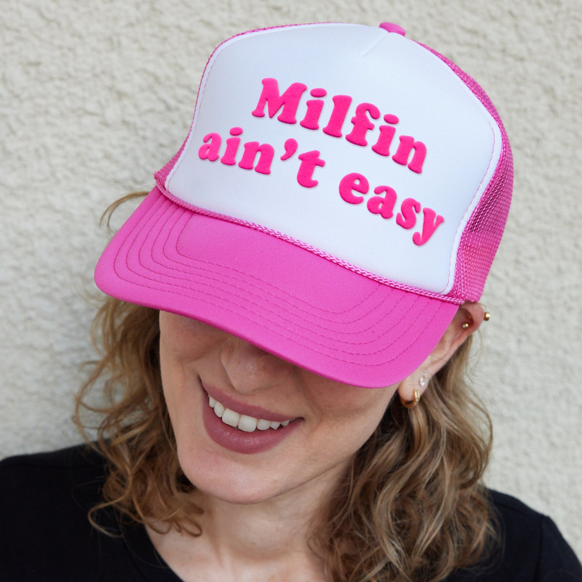 a woman wearing a pink and white trucker hat