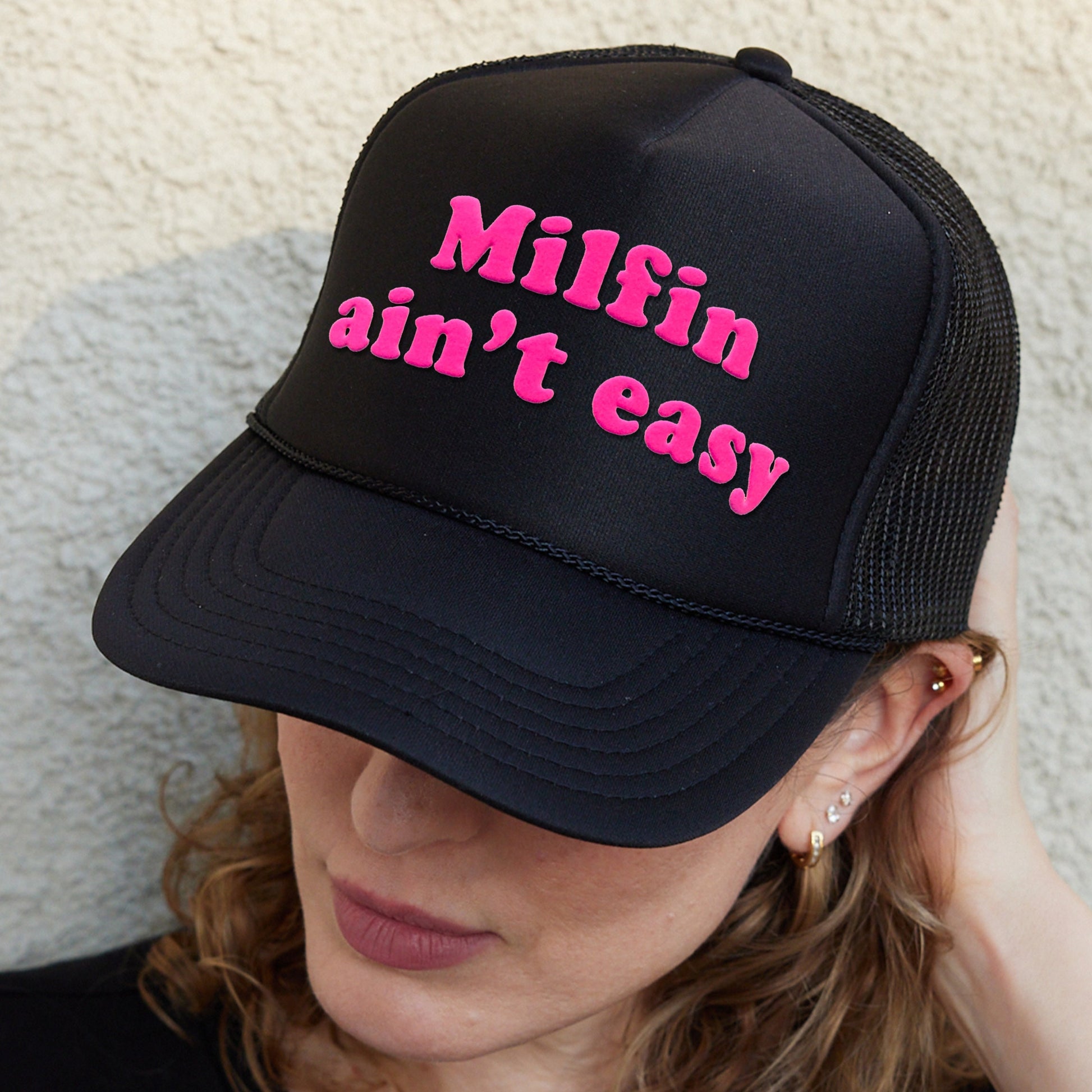 a woman wearing a black hat with pink writing on it