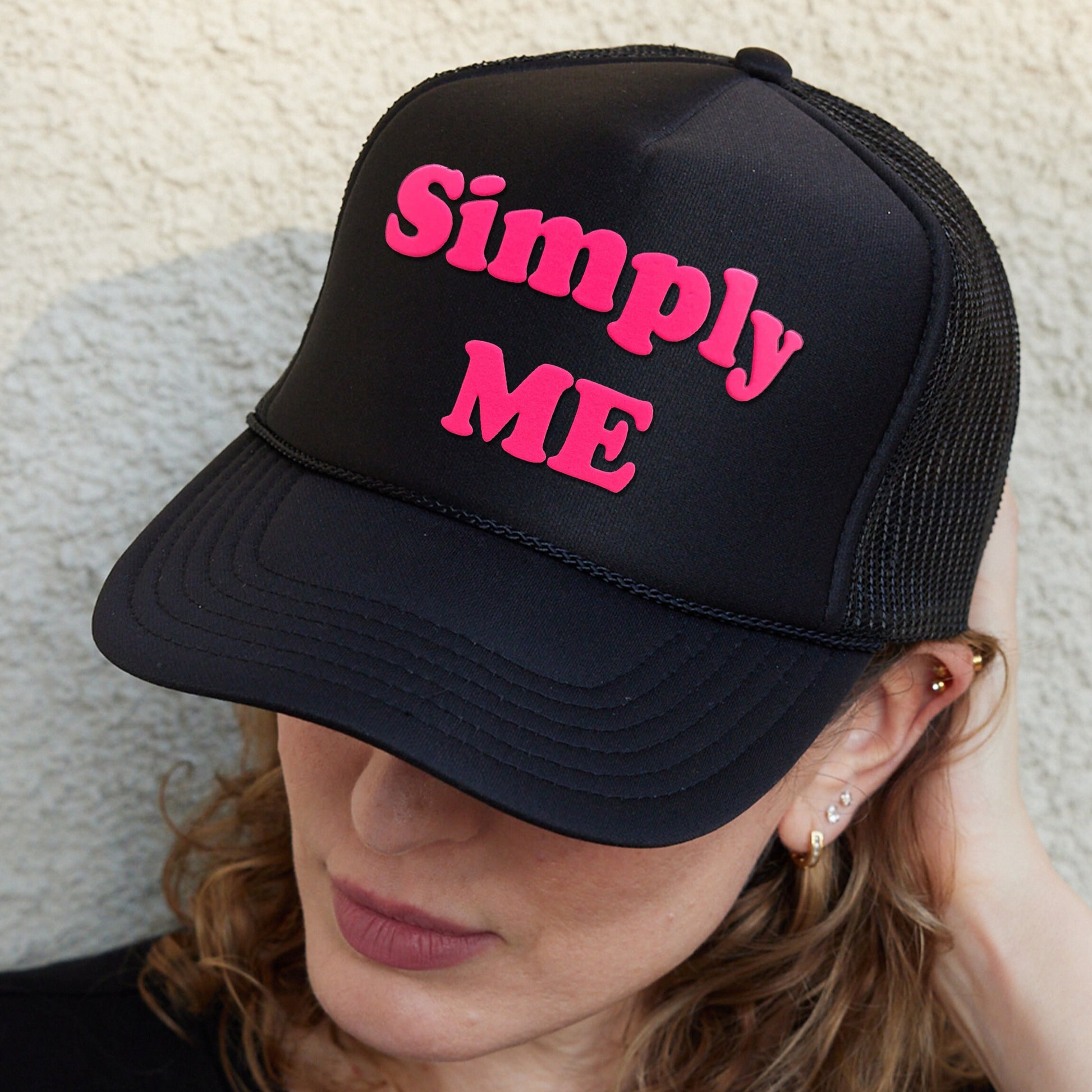 a woman wearing a black and pink trucker hat