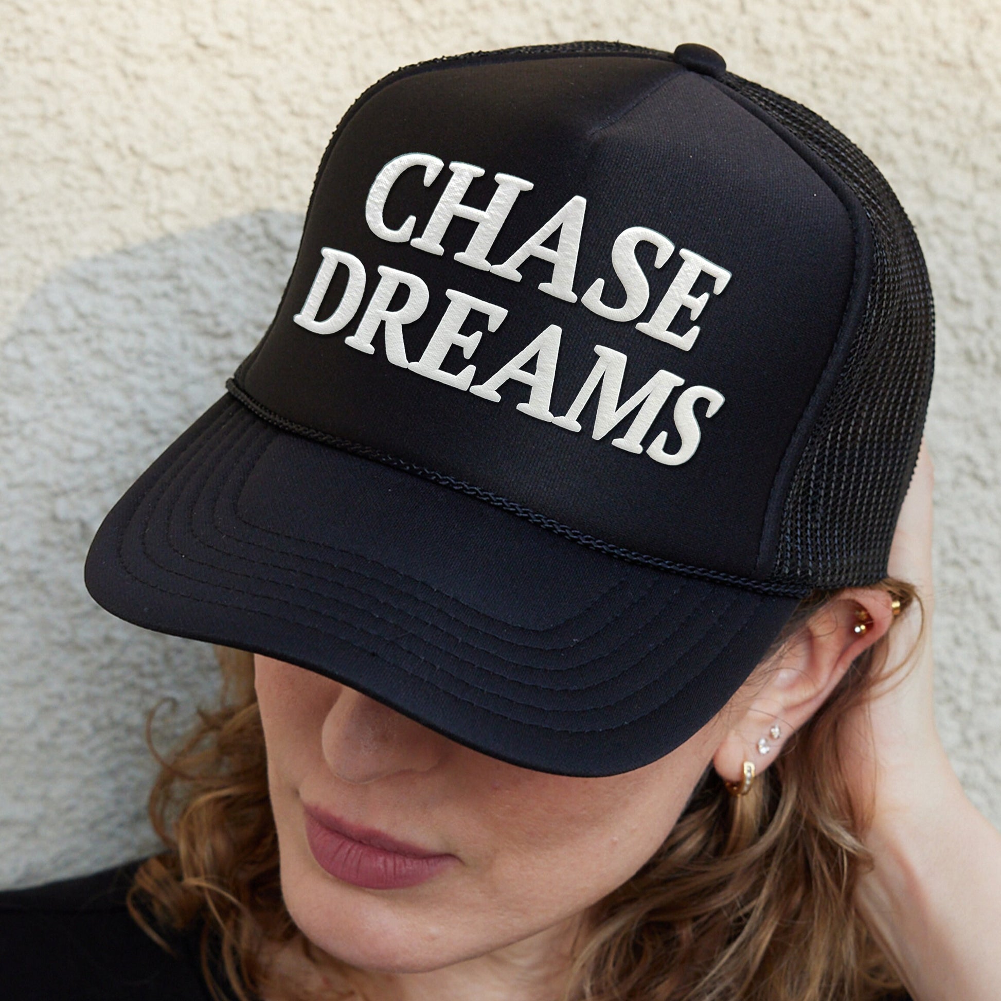 a woman wearing a black hat that says chase dreams