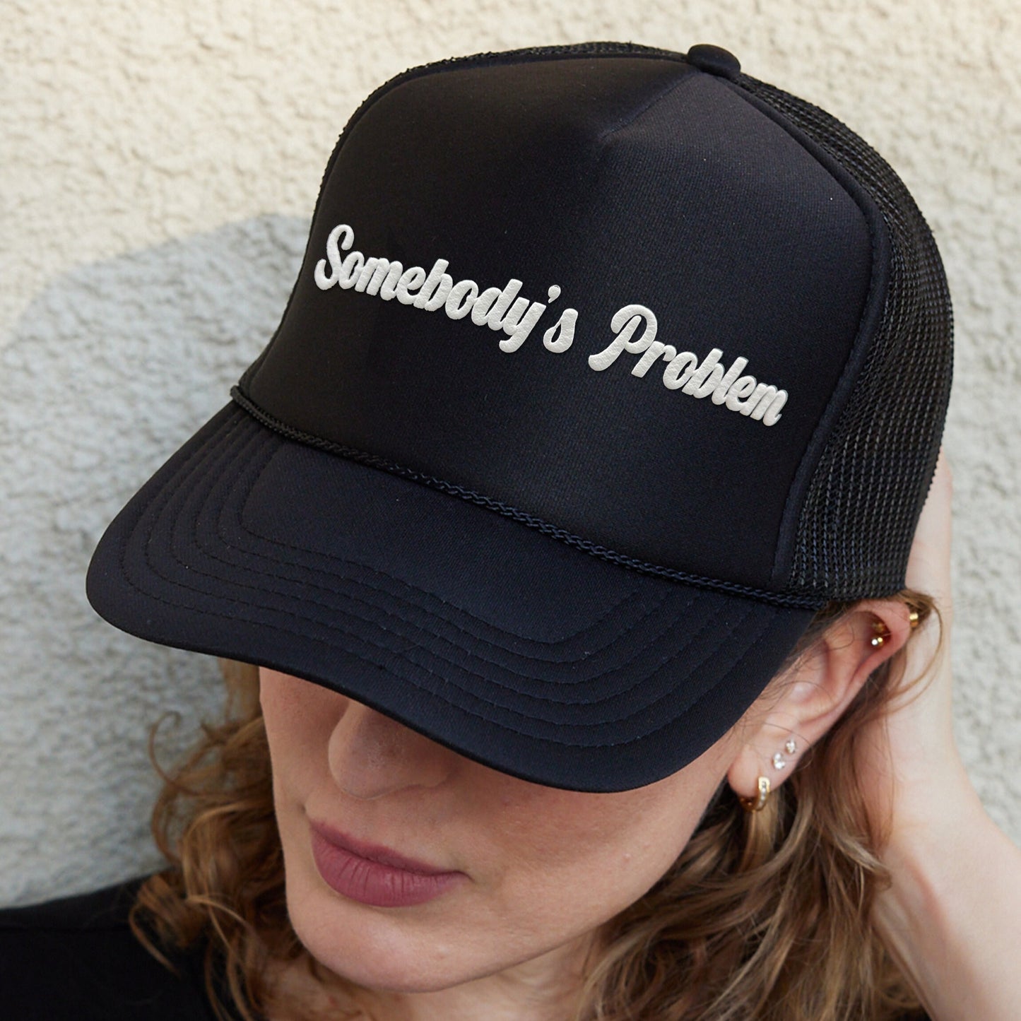 a woman wearing a black hat with somebody&#39;s problem written on it