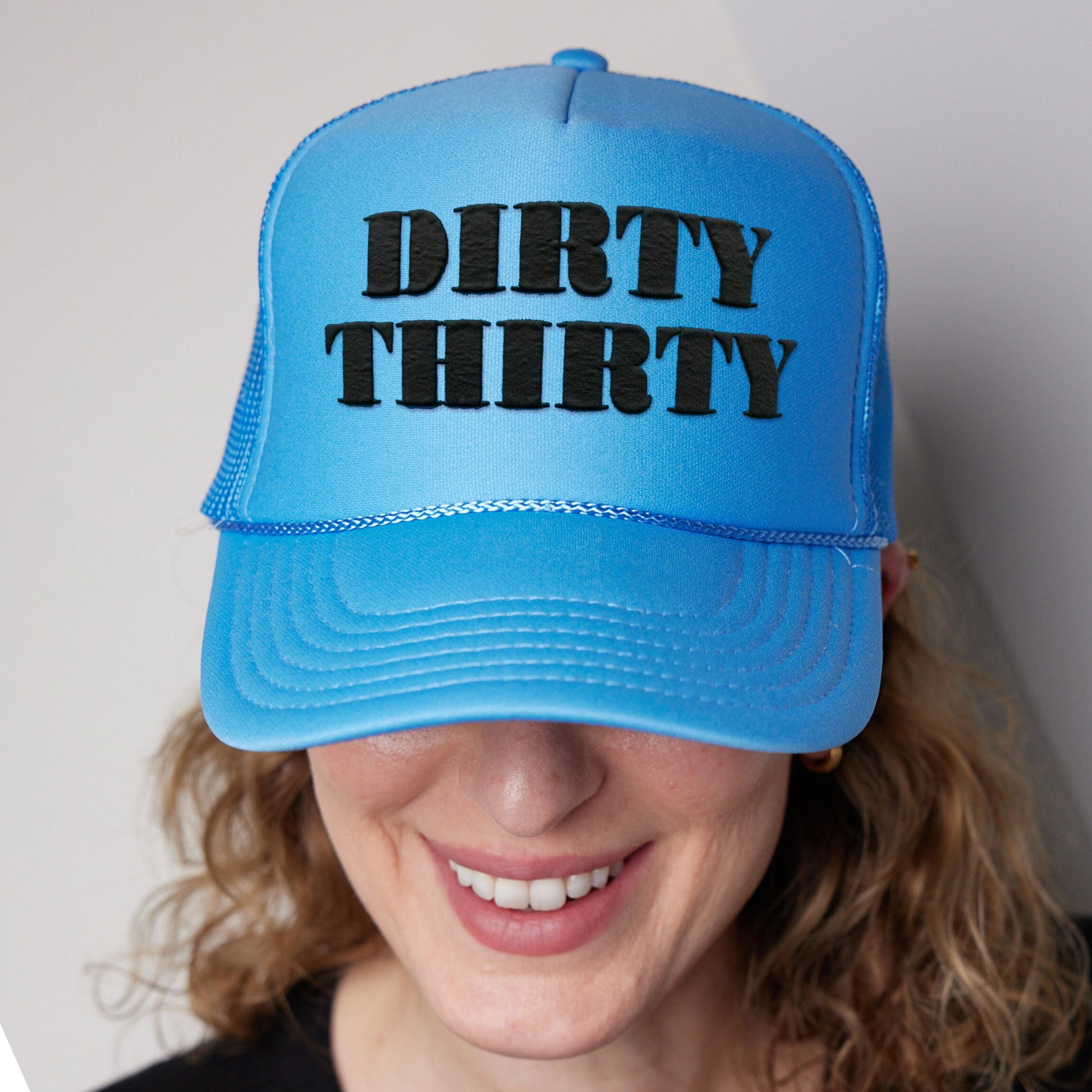 a woman wearing a blue hat with the word dirty thirty printed on it