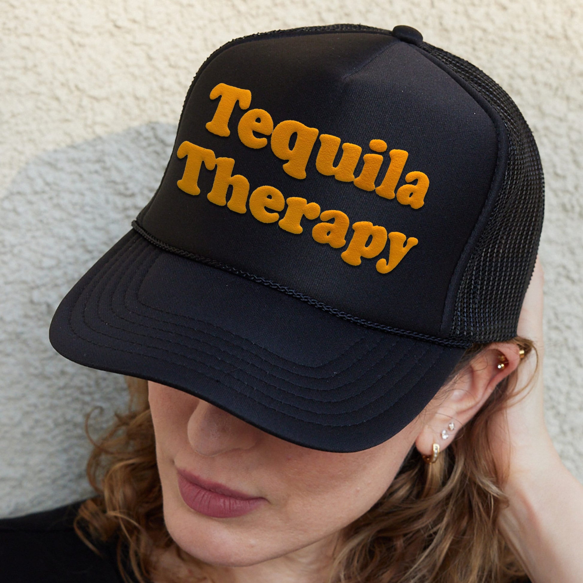 a woman wearing a black hat with the words tequila therapy on it