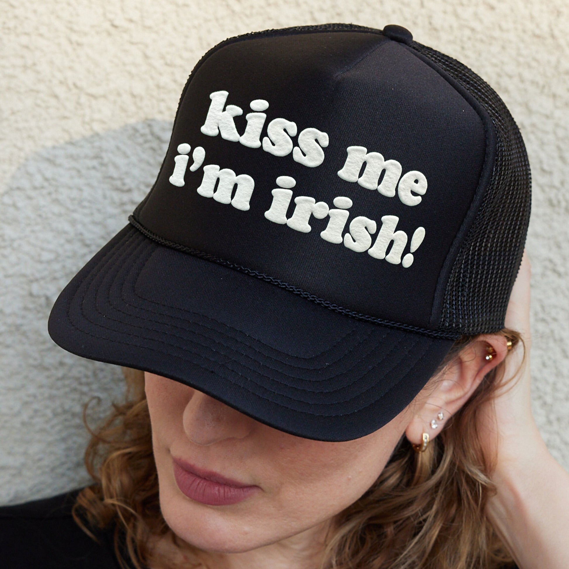 a woman wearing a black hat with the words kiss me i&#39;m irish on