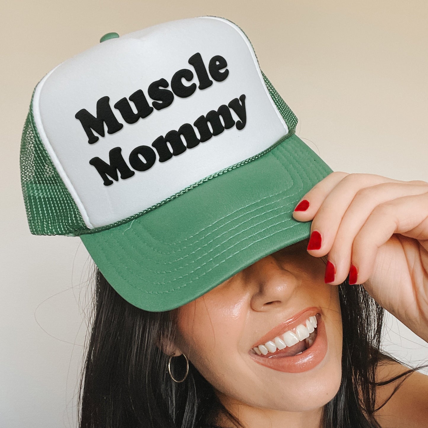 a woman wearing a green and white hat with the words muscle mommy on it