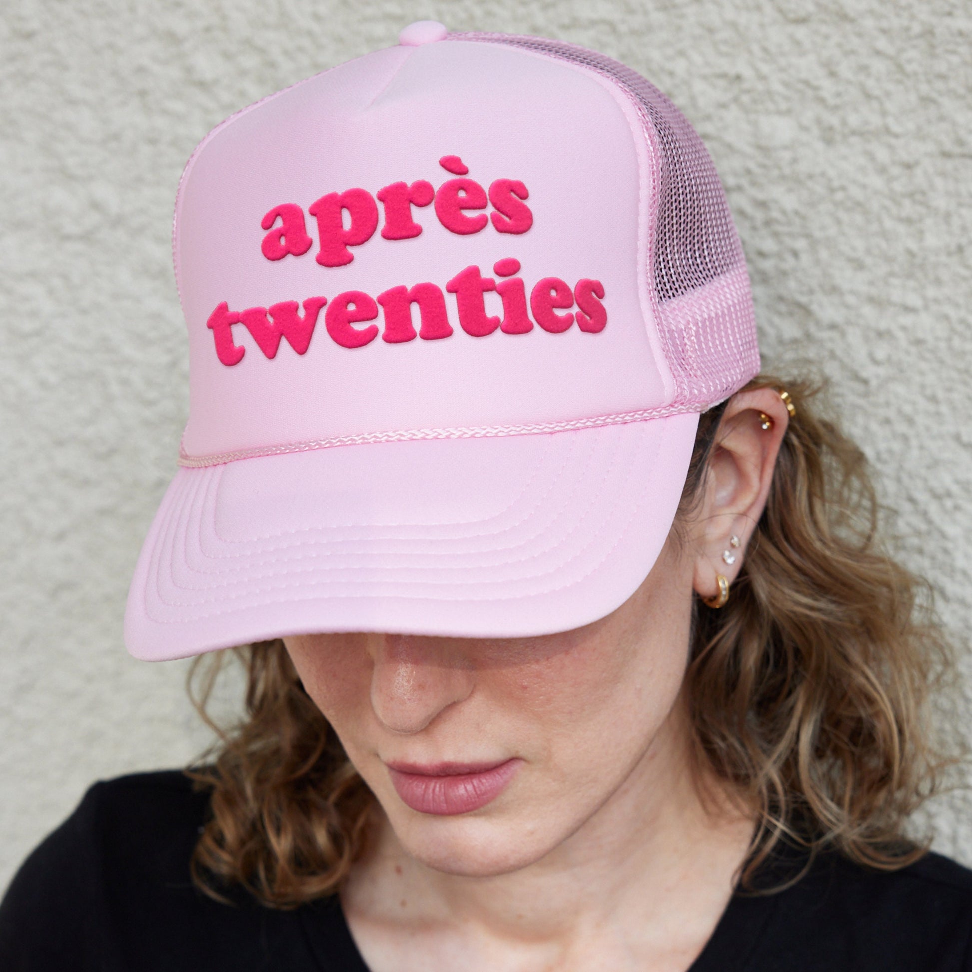 a woman wearing a pink hat that says apres twenty