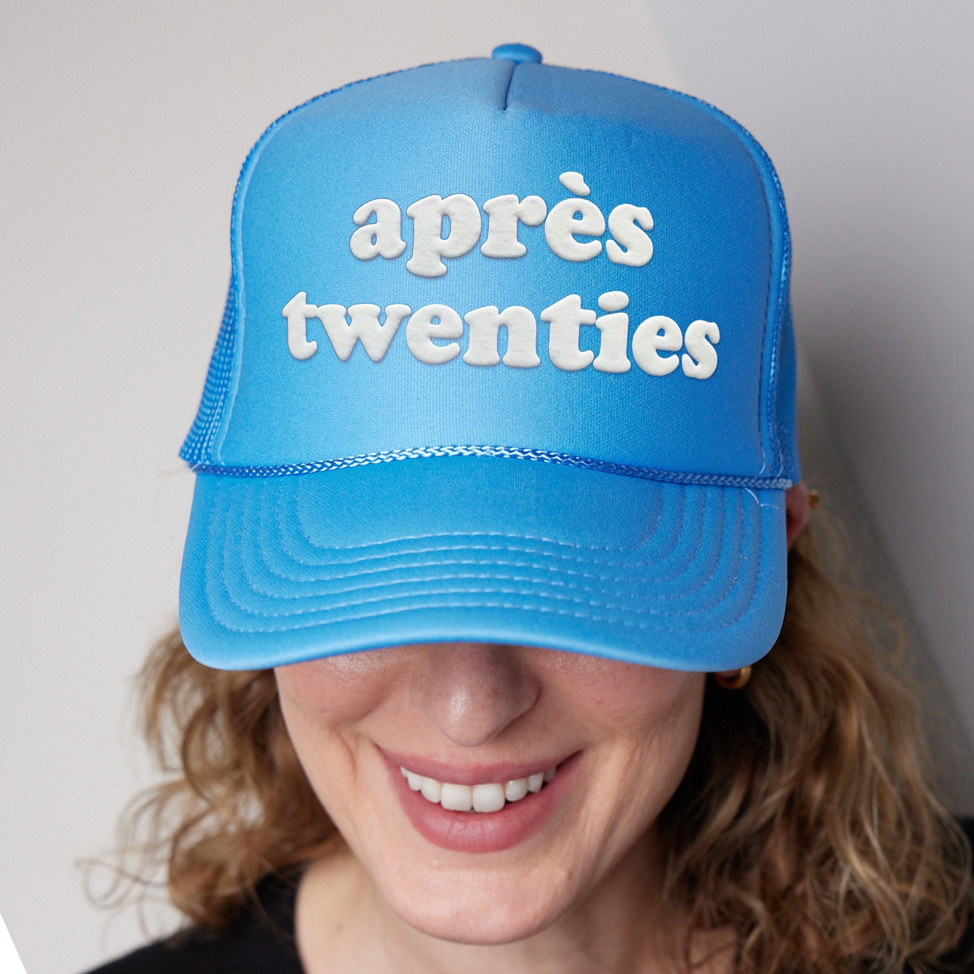 a woman wearing a blue hat with the words apres twenties on it