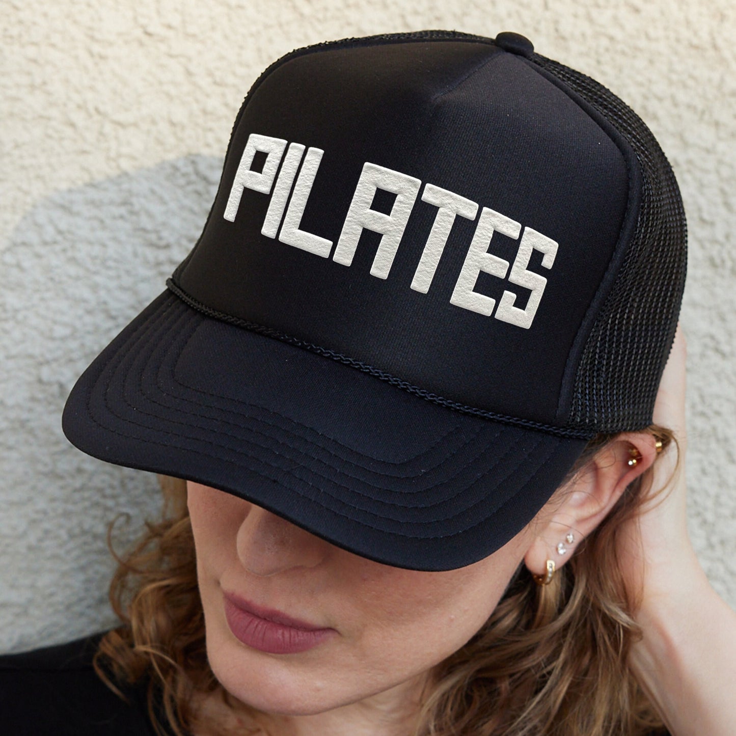 a woman wearing a black hat with white letters on it