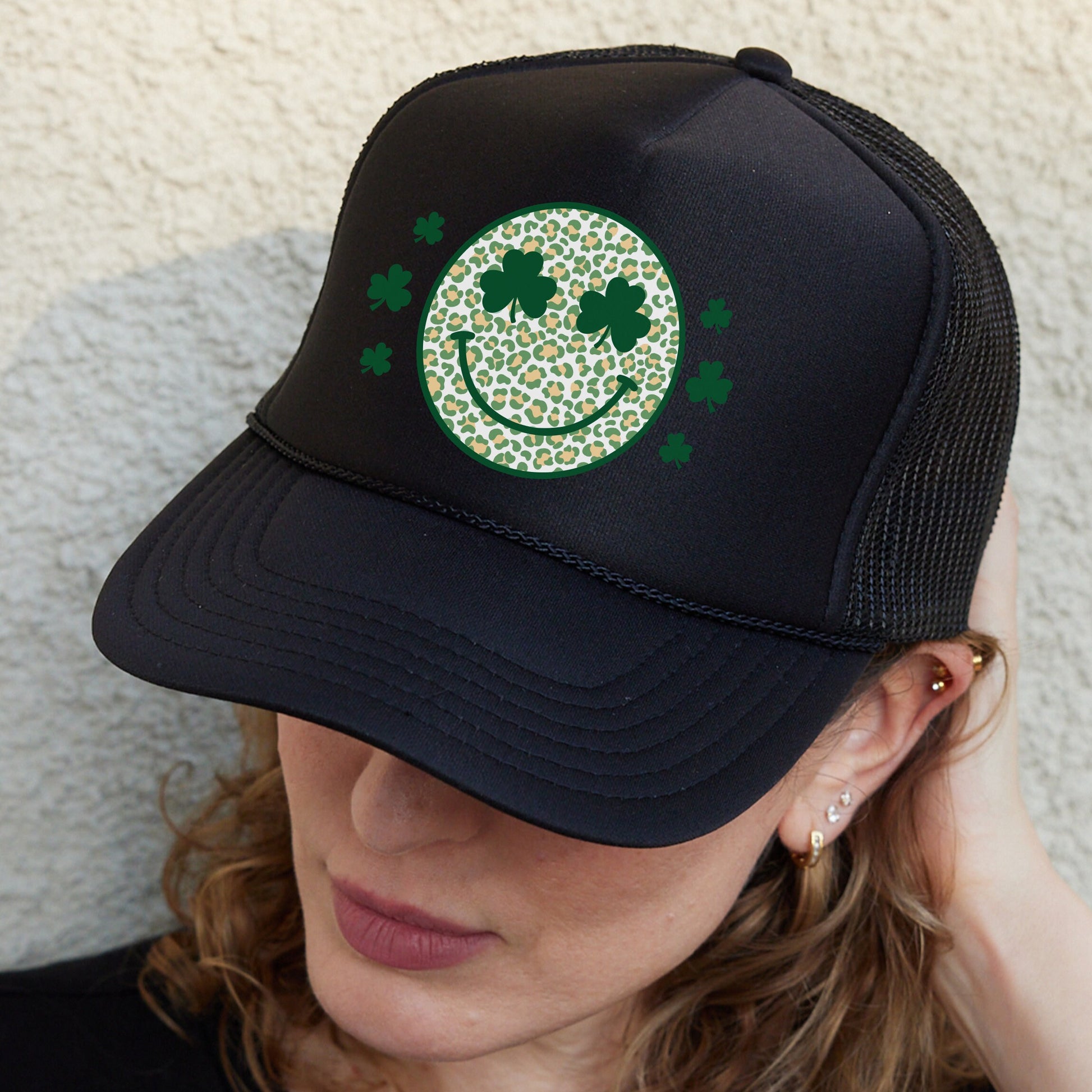 a woman wearing a black hat with a green smiley face
