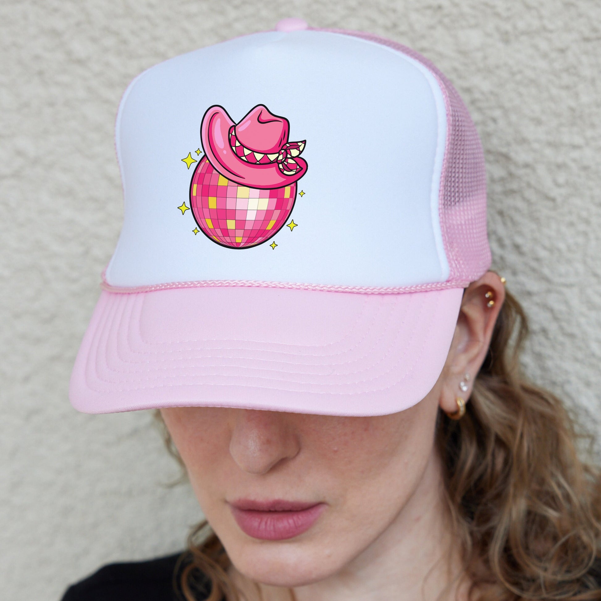 a woman wearing a pink and white trucker hat